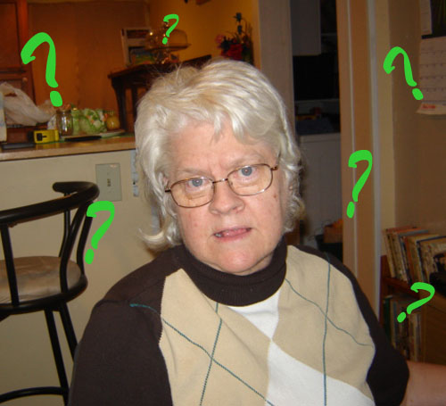 Carole wearing brown sweater. Perplexed look on the face. Surrounded by large green question marks.