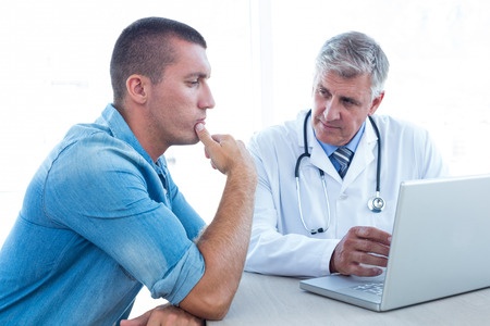 Worried man in his 20s meeting with his doctor in medical office.