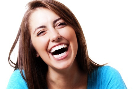 Young woman in blue shirt laughing heartily.