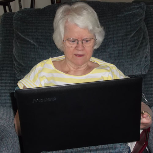 Carole in her recliner using her laptop
